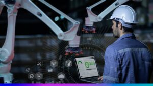 Indústria 4.0 com trabalhador monitorando robôs industriais e analisando dados em laptop, simbolizando automação e transformação digital no setor industrial.