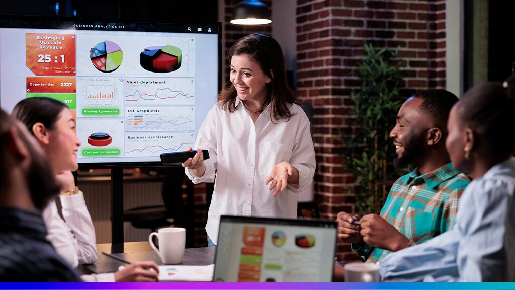 Equipe de marketing analisando gráficos em uma reunião com painel de dados ao fundo, representando cases de sucesso na implementação de plataformas CDP.