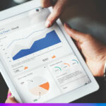 Pessoa utilizando um tablet com dashboard de métricas e gráficos, representando a integração entre Google Analytics 4 (GA4) e CDP para aprimorar insights de clientes.