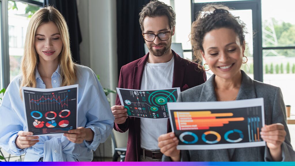 Três profissionais analisando relatórios com gráficos coloridos, representando a aplicação de dados e métricas na melhoria da experiência do cliente.