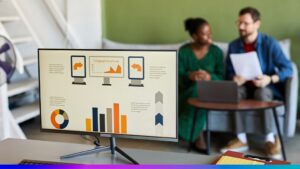 Monitor exibindo gráficos e infográficos de desempenho com profissionais ao fundo, representando a análise da qualidade de dados com uso de CDP.