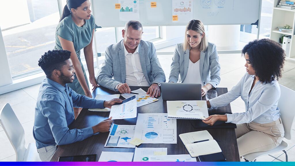 Equipe de profissionais analisando relatórios e gráficos em uma reunião corporativa, representando a aplicação da governança de dados na tomada de decisões.