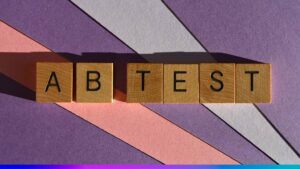 Blocos de madeira com as letras “A B TEST” sobre fundo colorido, simbolizando o conceito de experimentos de marketing digital.