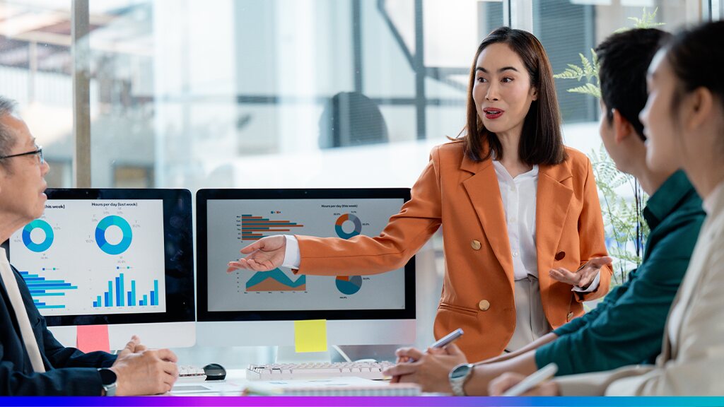 Profissional apresentando gráficos de desempenho em reunião de equipe, simbolizando análise e cálculo de ROI de marketing.