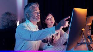 Dois profissionais analisando dashboards em monitor, simbolizando gestão e monitoramento de dados em uma Enterprise CDP.