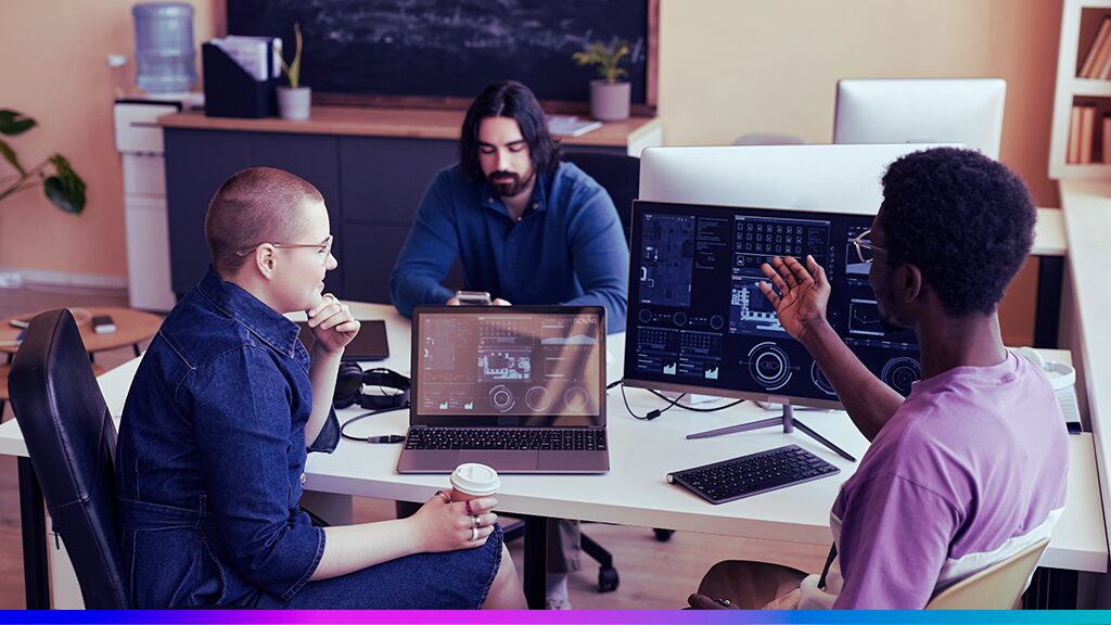 Equipe de profissionais em escritório discutindo dados exibidos em telas e notebooks, representando a arquitetura e integração de uma plataforma Enterprise CDP