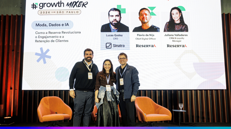 Lucas Godoy, Juliana Valladares e Flavio de Nijs diante do painel do case Reserva no Growth Mixer São Paulo 2026.